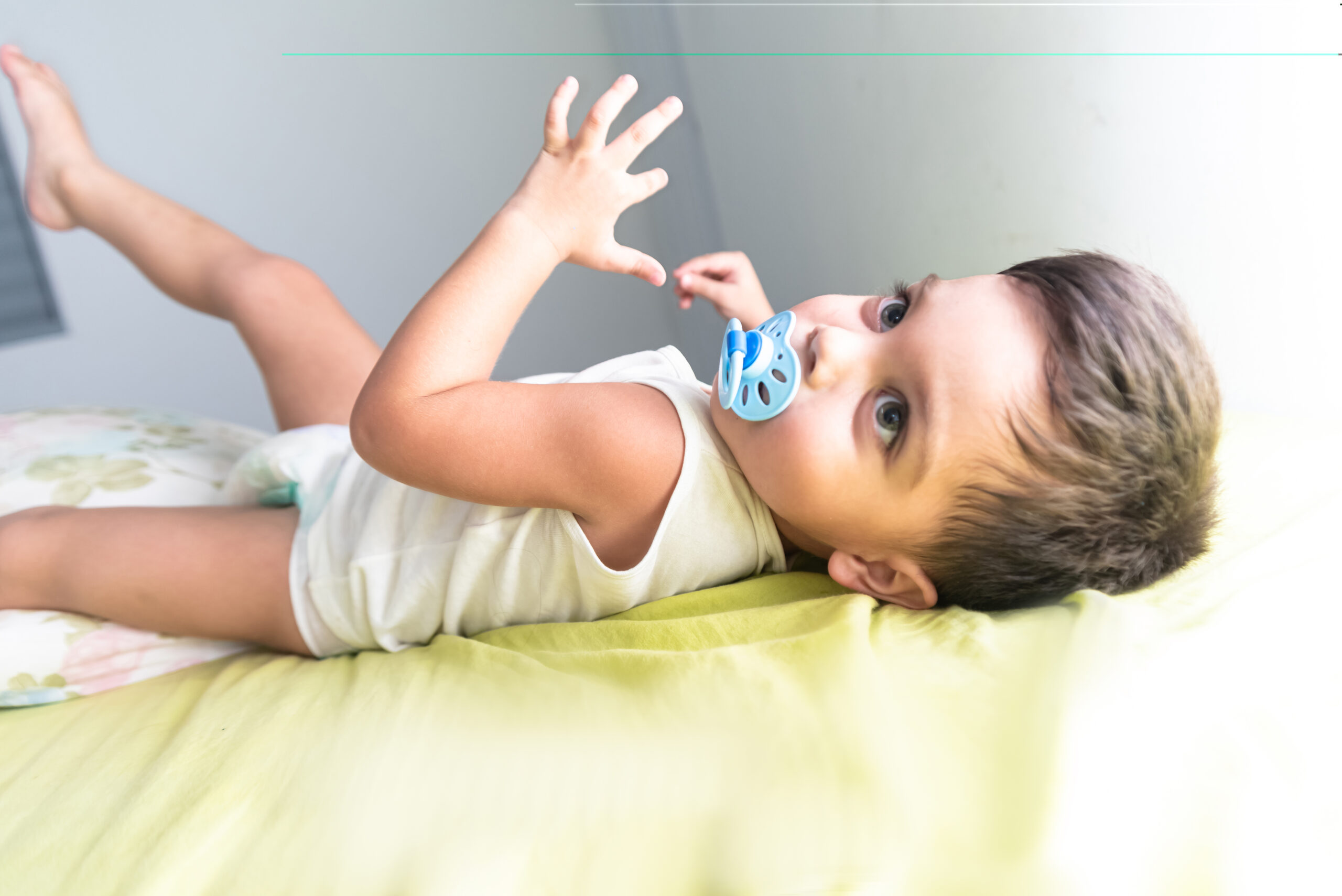 Baby boy in white t-shirt lying on bed